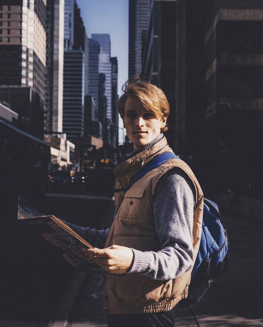 Collin on a city street with a backpack and a map